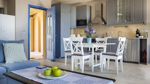 Una cocina moderna con armarios grises, una mesa de comedor con sillas blancas y una puerta azul que da a otra habitación.
