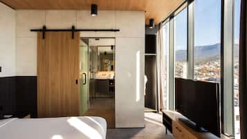 A modern hotel room with a large bed, a TV, and a city view.