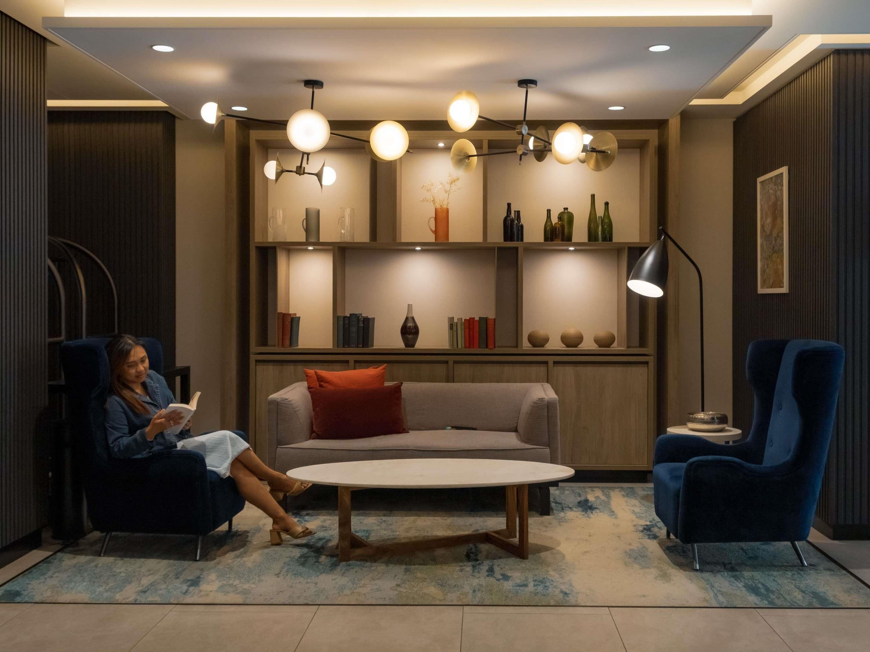 A modern living room with a sofa, two armchairs, a coffee table, and a bookshelf.