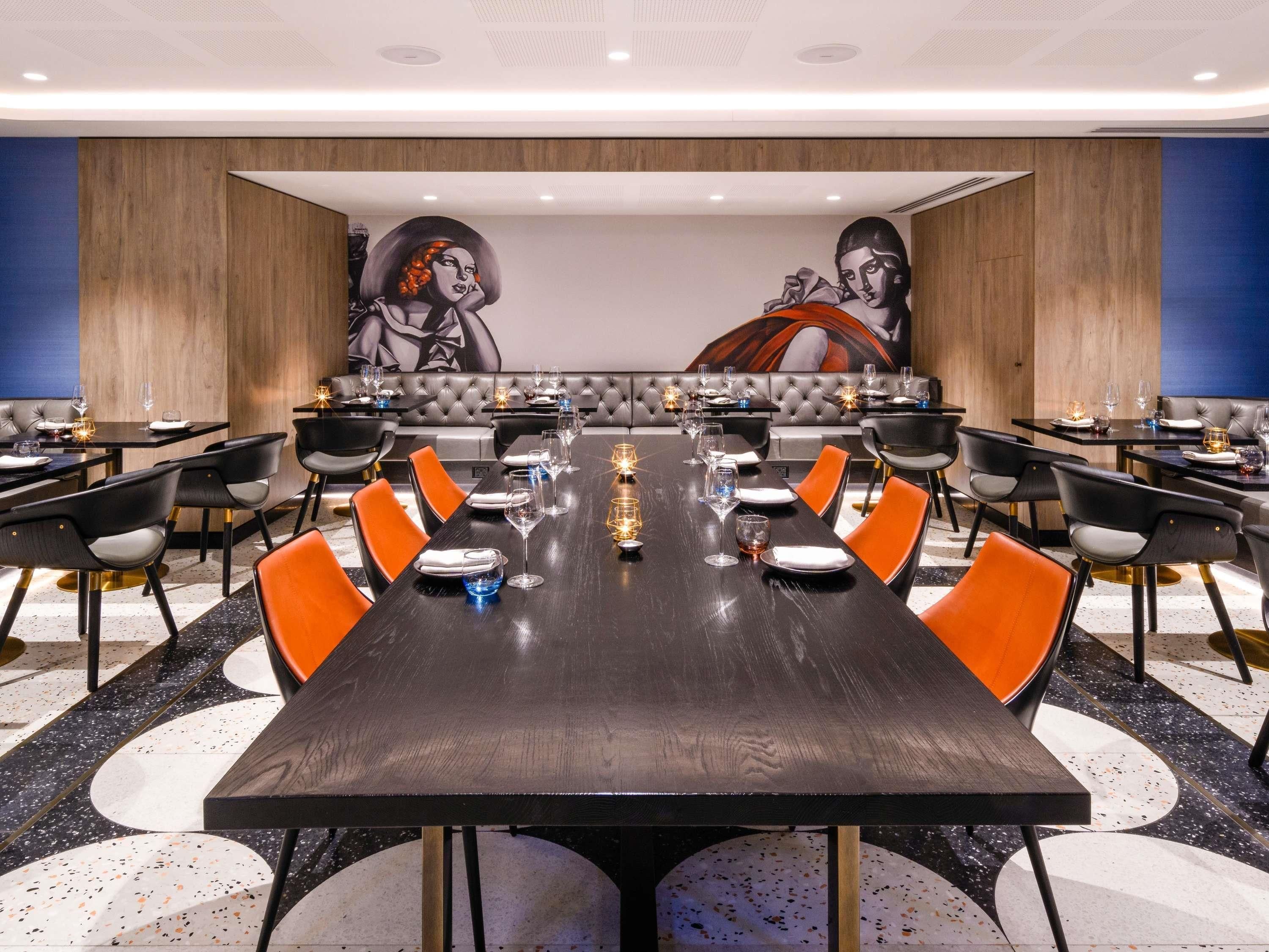 A conference room with a long table, multiple chairs, and a large mural on the wall.