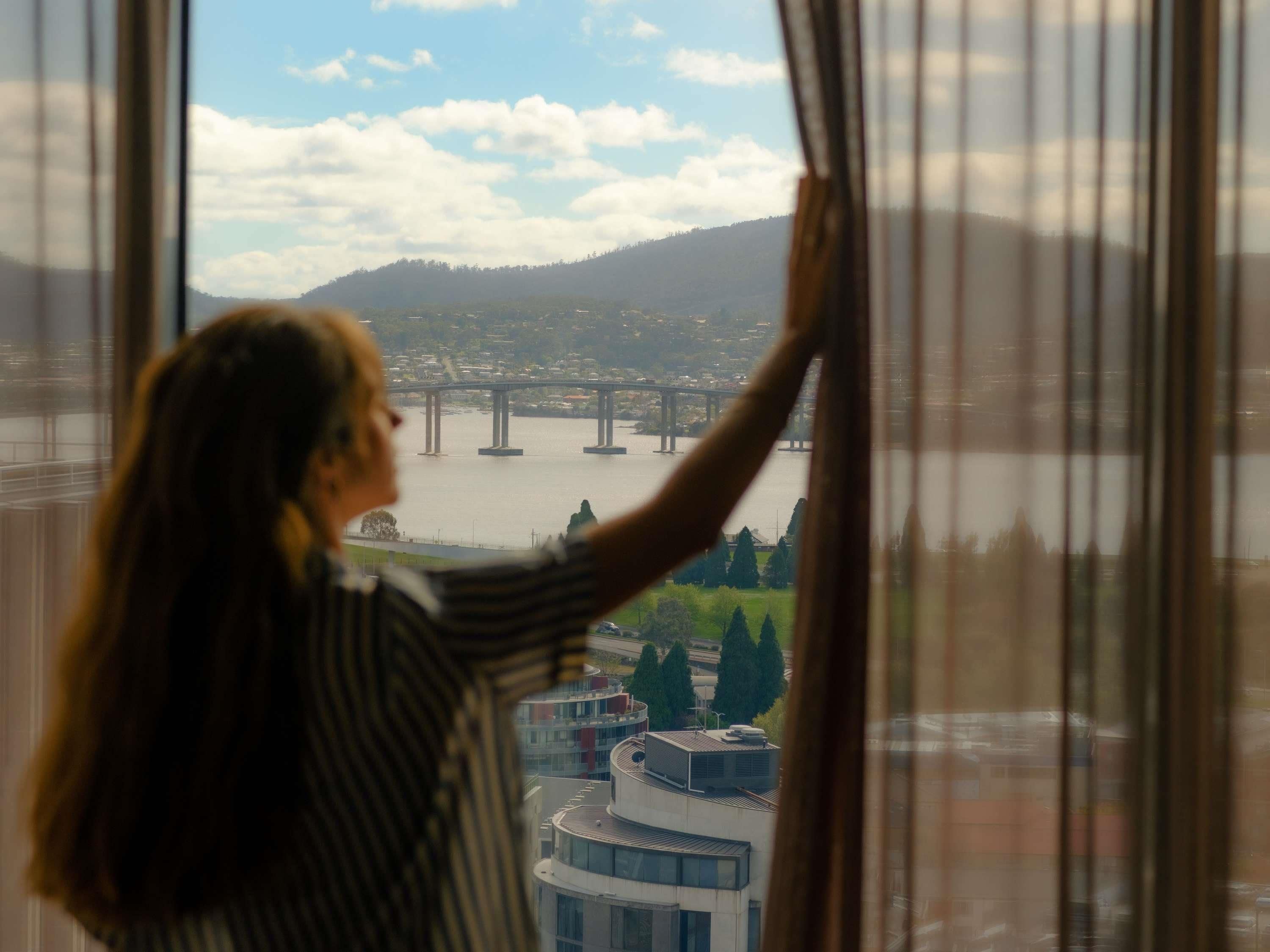A person looking out of a window at a bridge and buildings.
