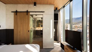 Una habitación de hotel moderna con una cama grande, un televisor y vistas a la ciudad.