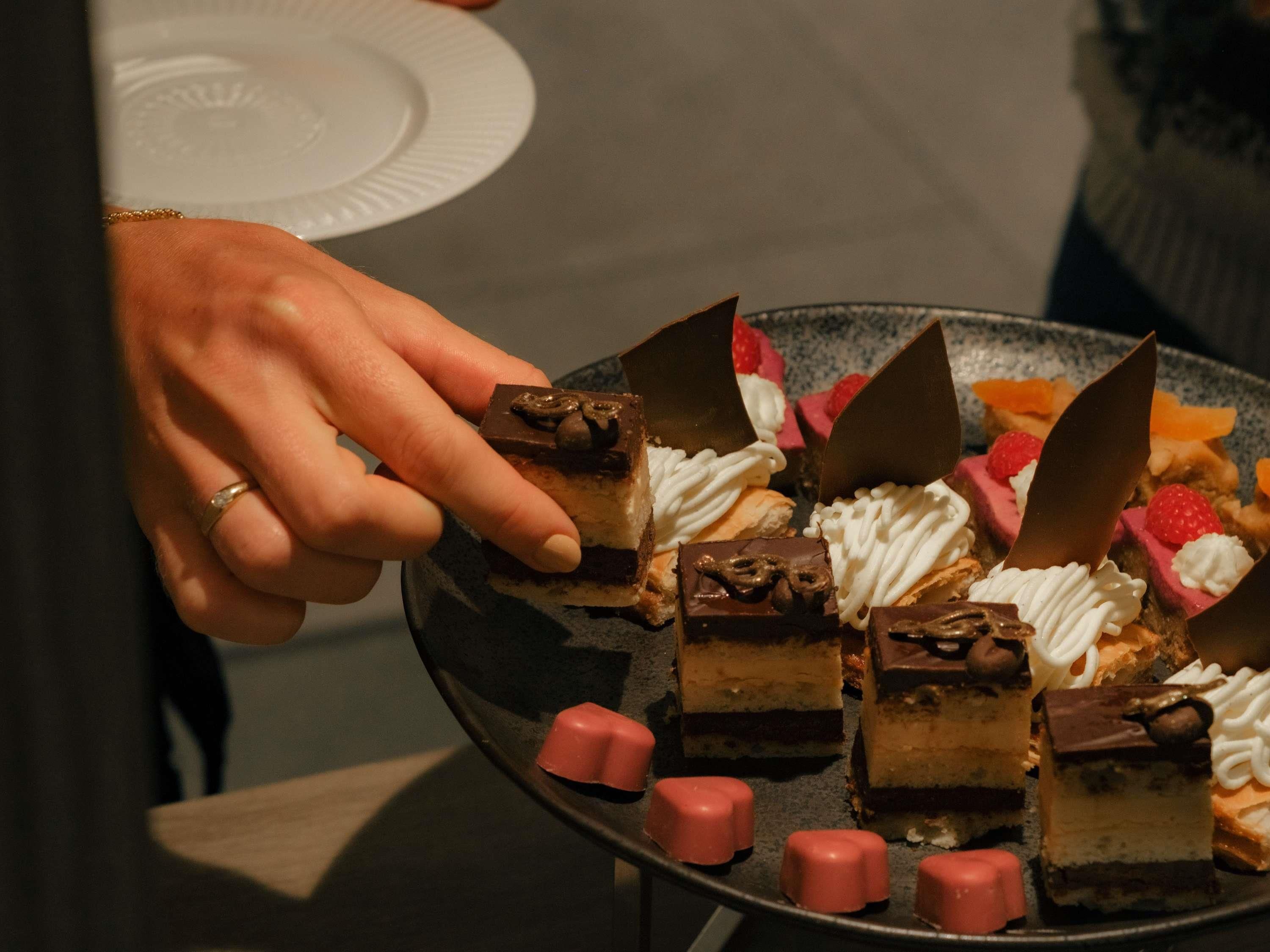 A hand holding a dessert plate with various sweets.