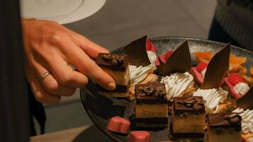 A hand holding a dessert plate with various sweets.