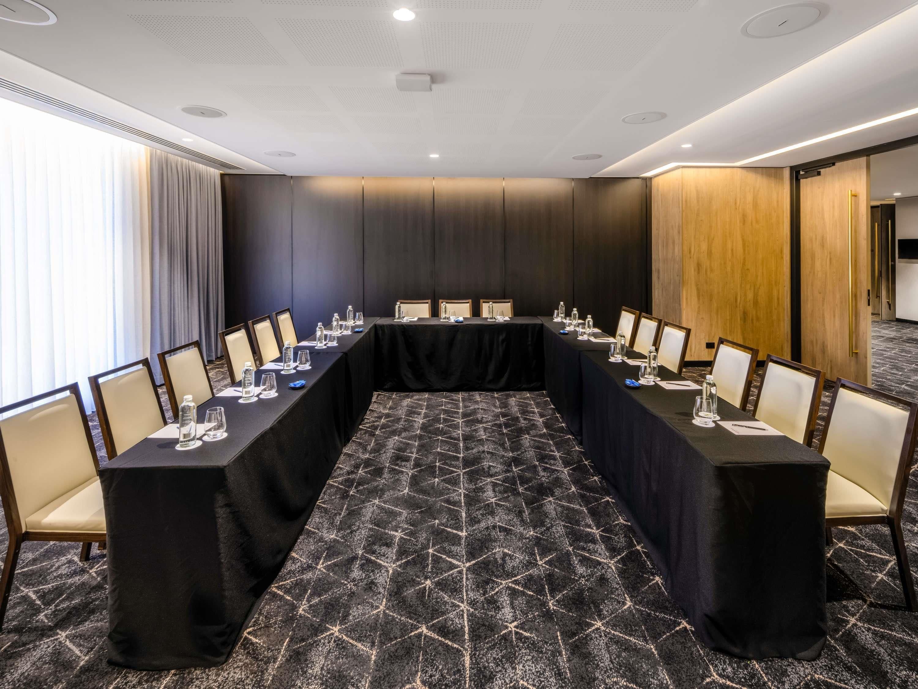 Uma sala de conferências com uma mesa comprida, cadeiras e piso coberto por carpete.
