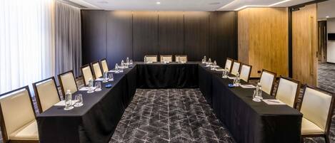 A conference room with a long table, chairs, and a carpeted floor.