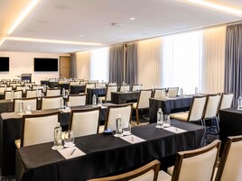 A conference room with tables set for meetings, equipped with water bottles and notepads.