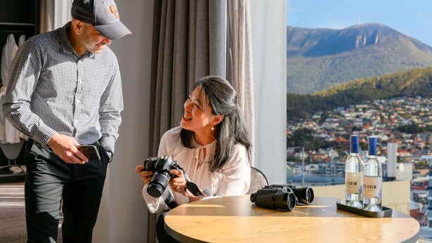Un hombre y una mujer en una habitación con un amplio ventanal que da a una ciudad y montañas.