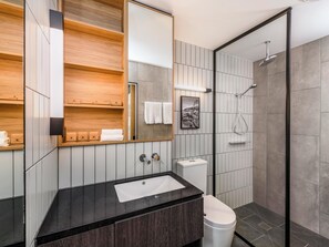 Een moderne badkamer met een zwart wastafel, een wit toilet en een douche met glazen wanden.