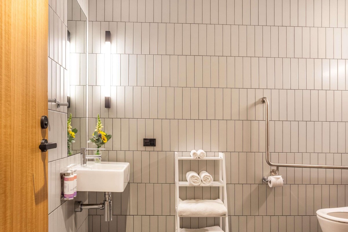 Een moderne badkamer met een wit wastafelmeubel, een handdoekhouder en een toilet.