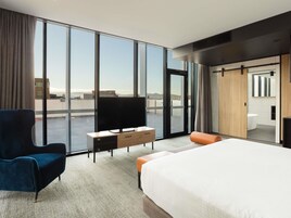 Una habitación de hotel moderna con una cama grande, televisión, escritorio y vistas a la ciudad.
