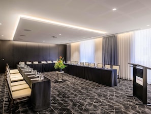 A conference room with a long table, chairs, and a podium. - Mövenpick Hotel Hobart (Hobart)
