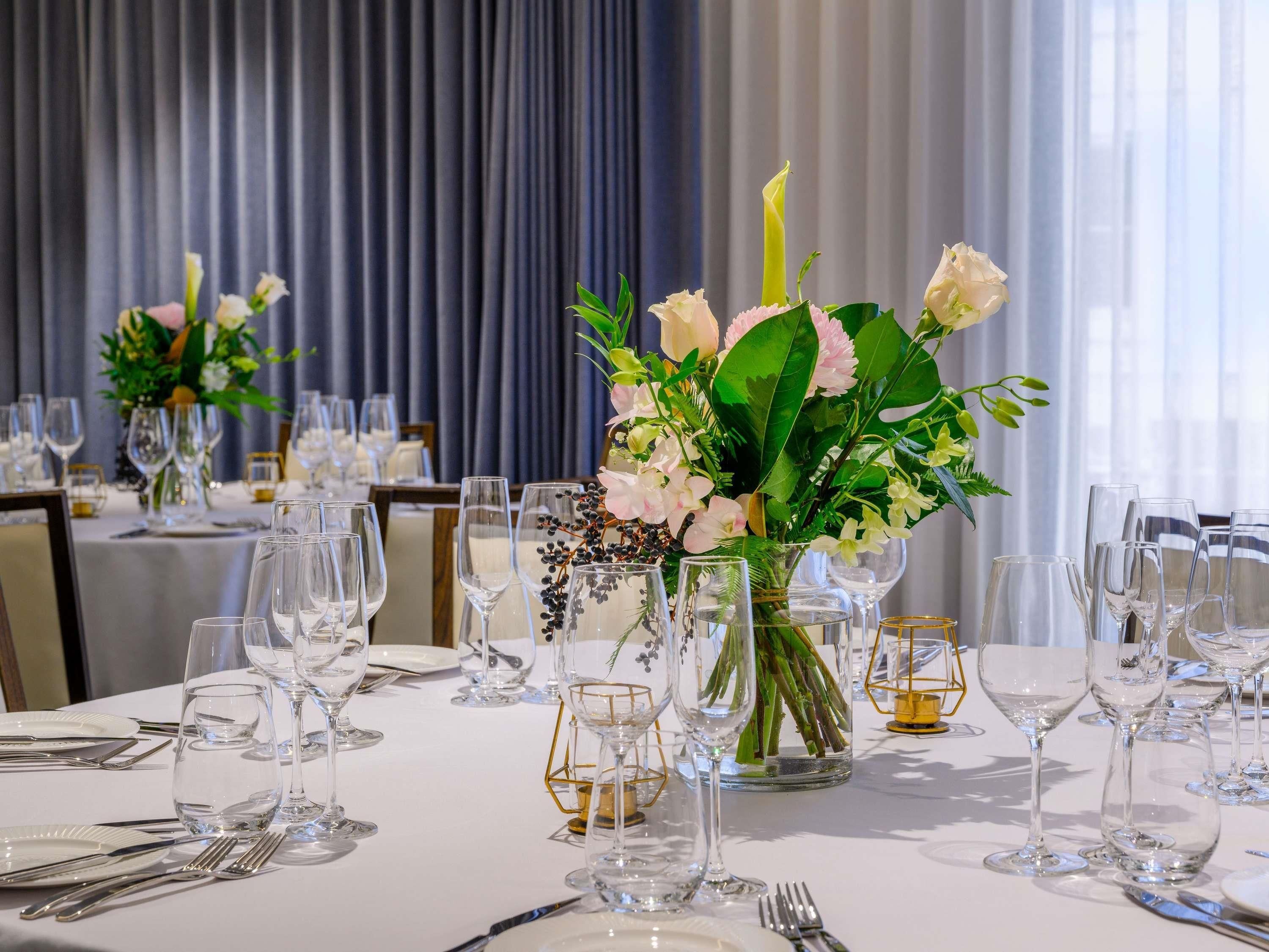 Une table dressée avec de la vaisselle transparente et un arrangement floral en guise de décoration centrale.