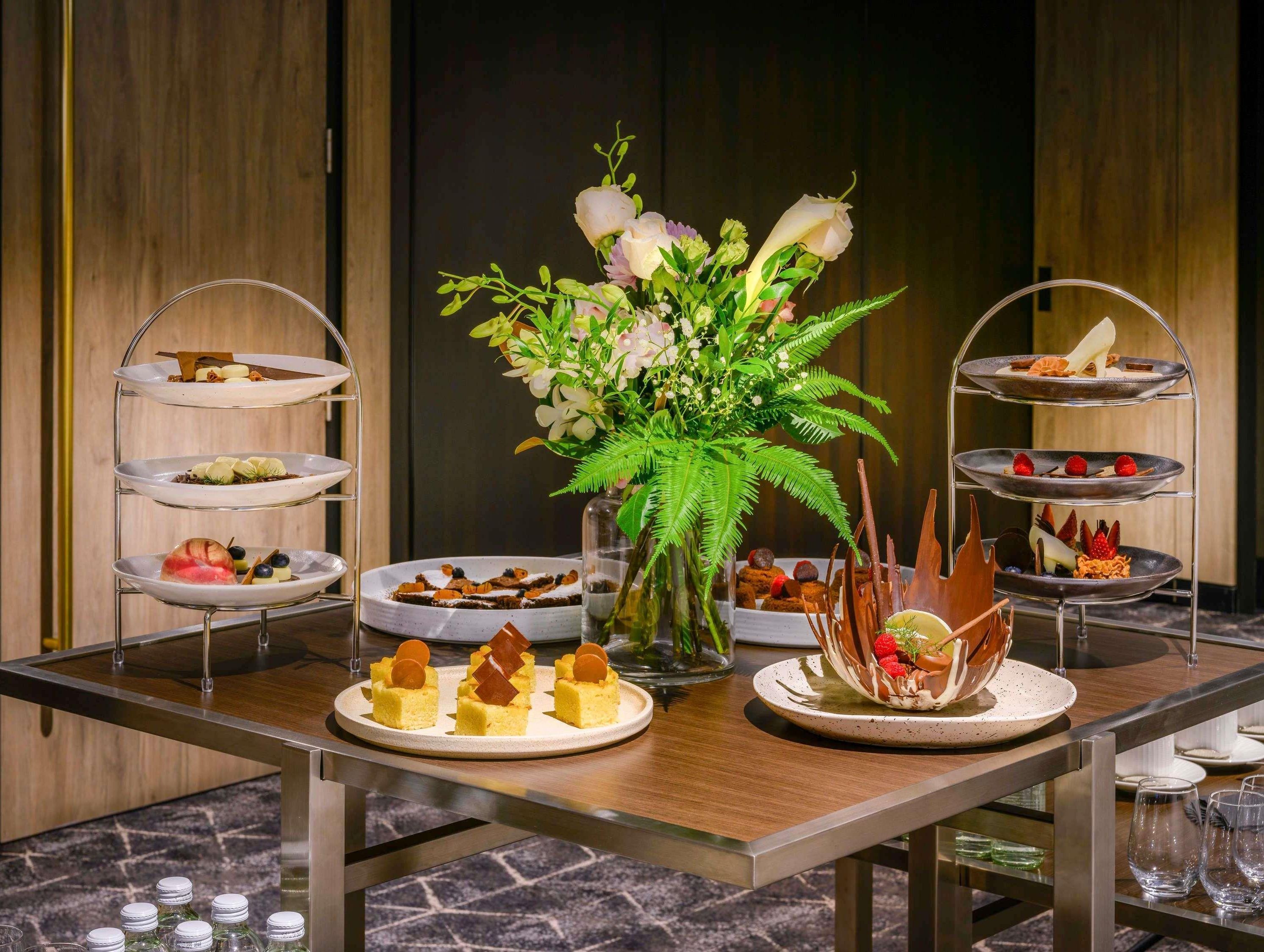 A multi-tiered dessert display with various sweet treats and a floral centerpiece.