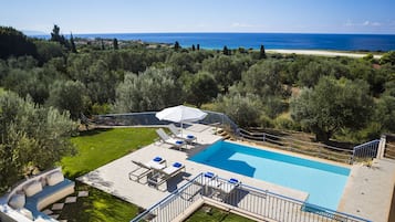 A pool area with lounge chairs and a view of the sea.