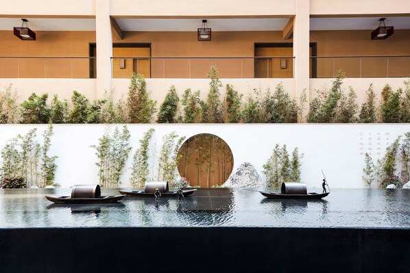 A serene indoor water feature with miniature boats and a circular wooden door. - Sheraton Maoming Romantic Beach Resort (Maoming)