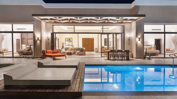 Une maison moderne dotée d’une piscine, d’un espace extérieur aménagé et d’un intérieur bien éclairé.