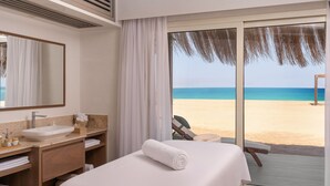 Une chambre d’hôtel avec un grand lit, une salle de bain avec un lavabo et un miroir, et une vue sur la plage.