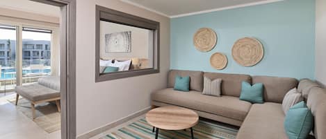 A modern living room with a sofa, a round coffee table, and a large window overlooking a pool.
