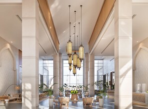 A spacious lobby with high ceilings, large windows, and a central chandelier.