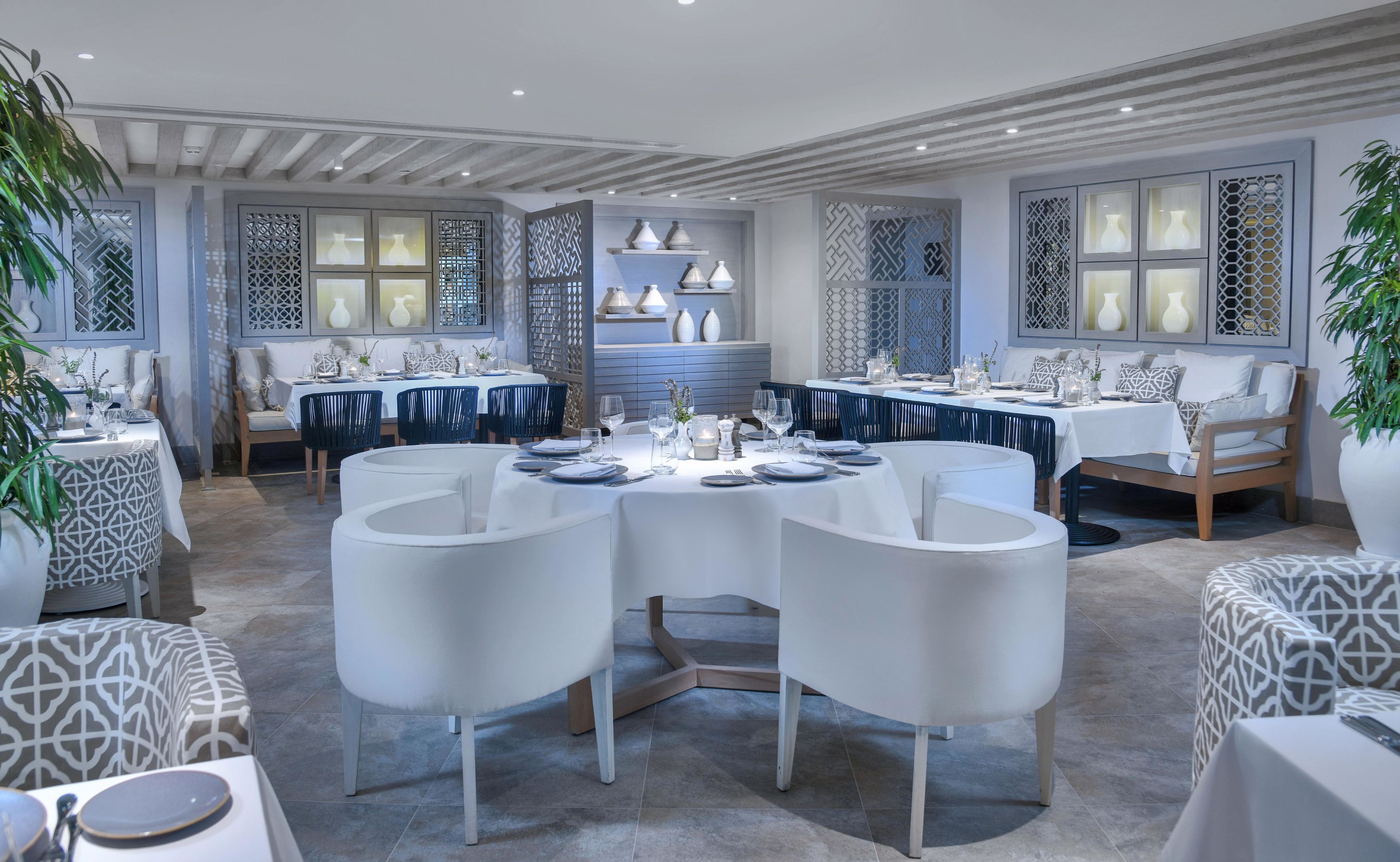 A dining area with round tables, chairs, and decorative vases.