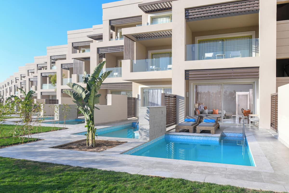 Um hotel moderno com várias varandas, piscina e áreas de estar ao ar livre.