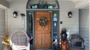A wooden front door with a wreath, two wicker chairs, a small bear statue, and a welcome sign. - Bear's Mountaintop Views 3 Bedroom Chalet by RedAwning (Robbinsville)