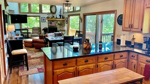 A spacious kitchen with a large island, wooden cabinets, and a dining area with a view of the outdoors. - Bear's Mountaintop Views 3 Bedroom Chalet by RedAwning (Robbinsville)