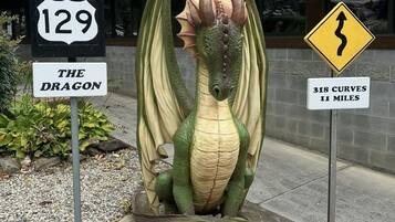 A dragon sculpture with road signs indicating '129 The Dragon' and '318 Curves 11 Miles'.
