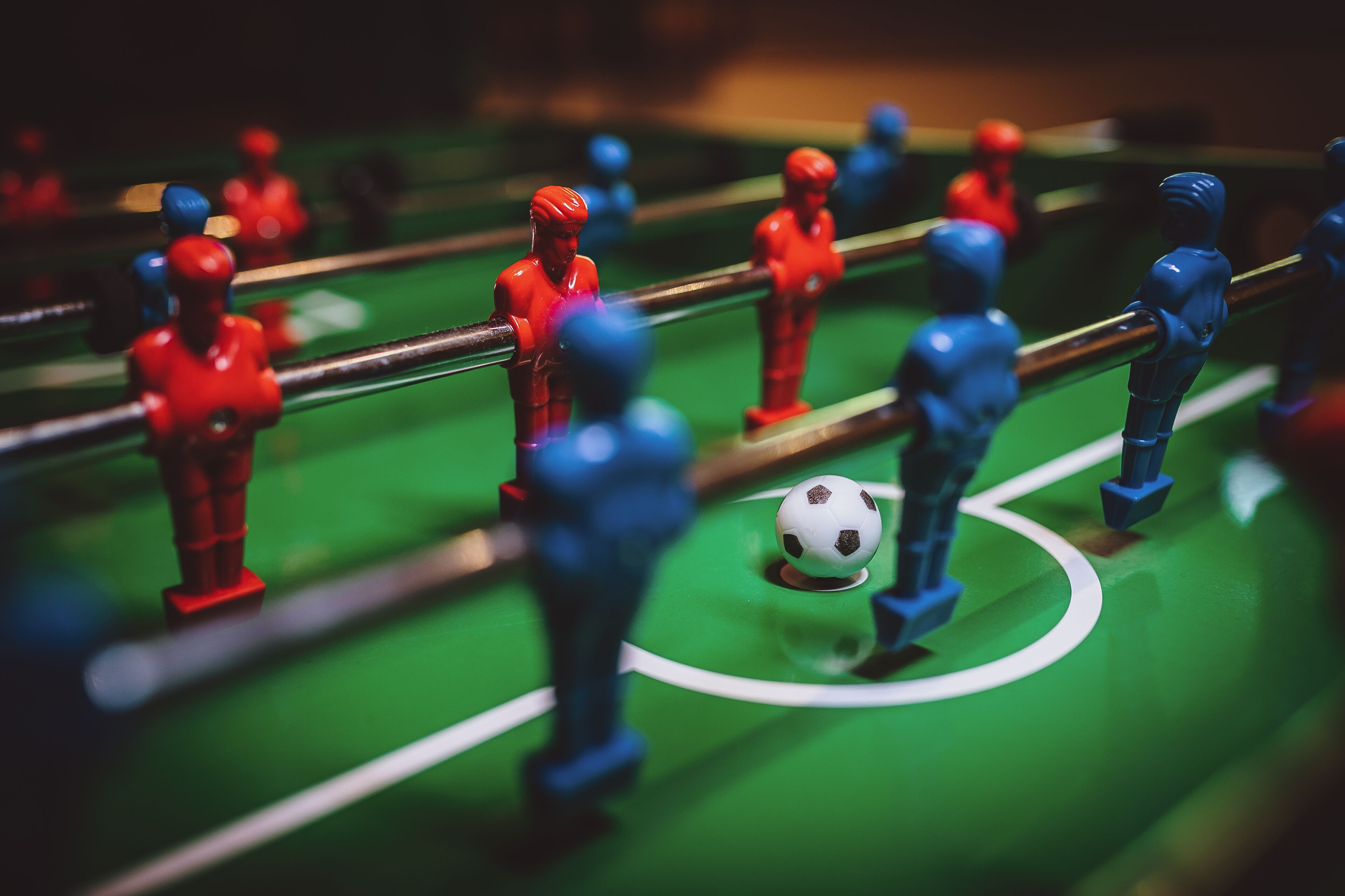 Un gros plan d’un baby-foot avec des joueurs rouges et bleus.