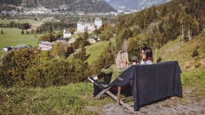 Un couple est assis à une table, avec une vue sur un village et des montagnes en arrière-plan.