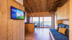 Un intérieur en bois avec un téléviseur fixé au mur, un canapé et un coin repas offrant une vue agréable.