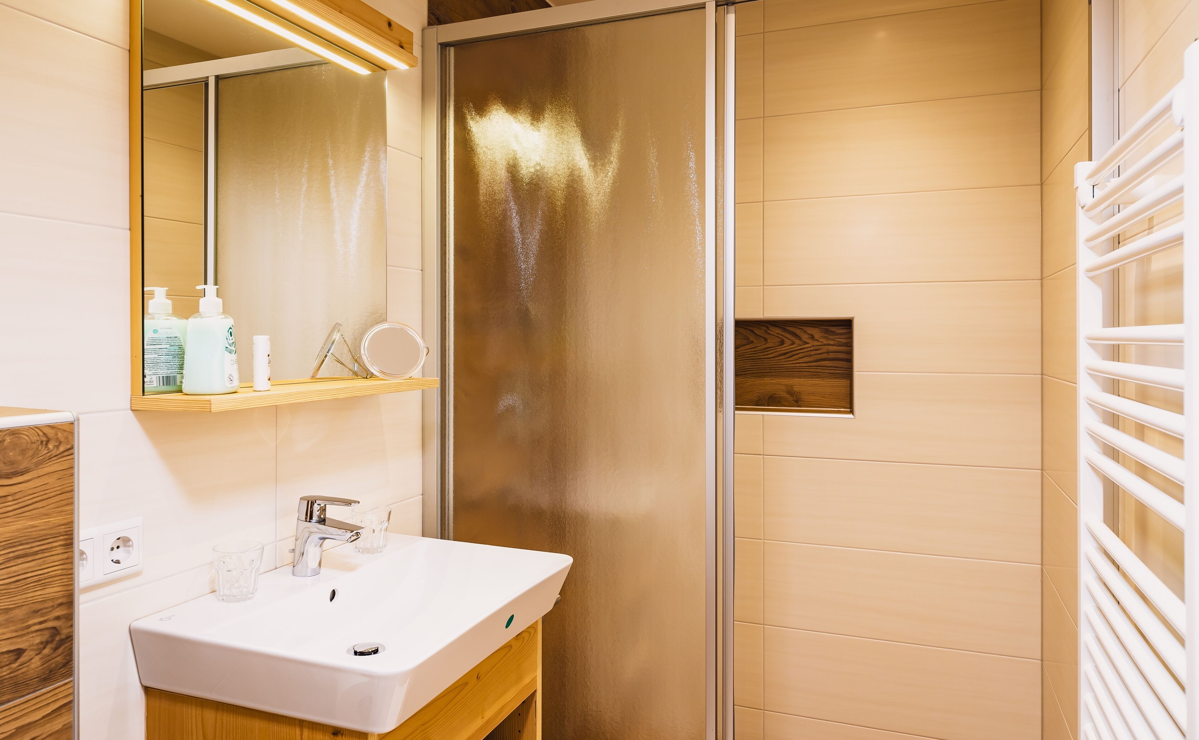 A modern bathroom with a white sink, mirror, and shower.