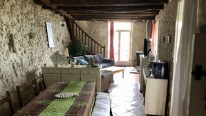 Une pièce rustique comprenant une table à manger, un canapé, un escalier et un coin cuisine.