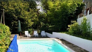 Une piscine avec trois chaises longues blanches et une couverture de piscine bleue.