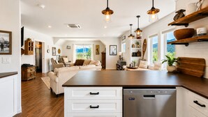 A modern kitchen with a central island, built-in dishwasher, and pendant lighting.