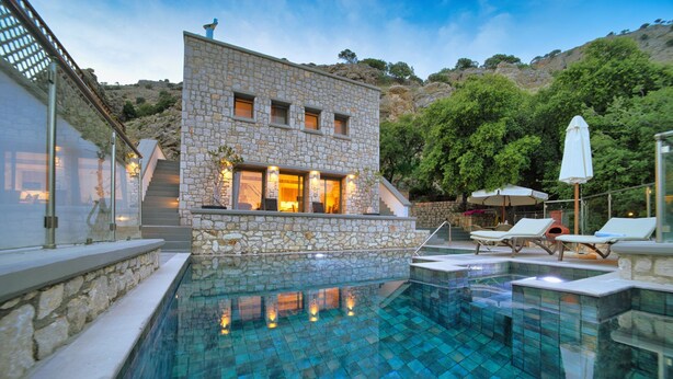 Ein Gebäude aus Stein mit Pool und Gartenmöbeln.