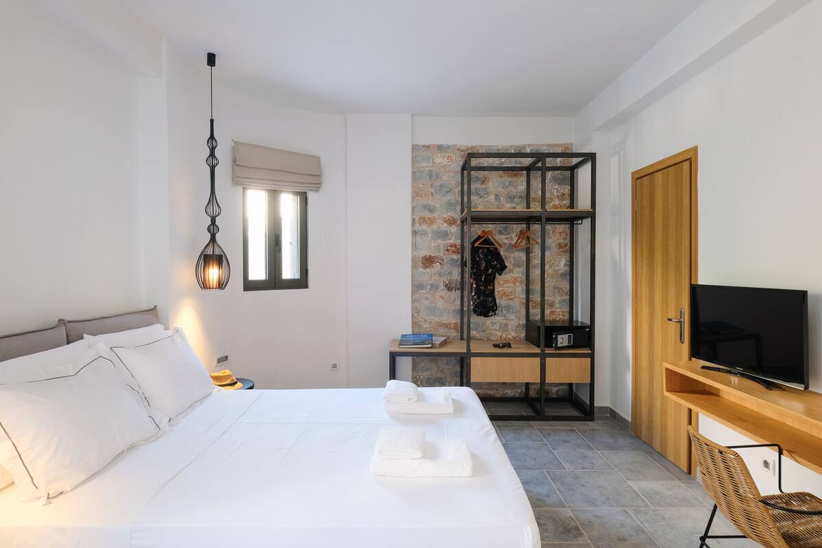 A hotel room with a bed, a TV, a desk, and a wardrobe.