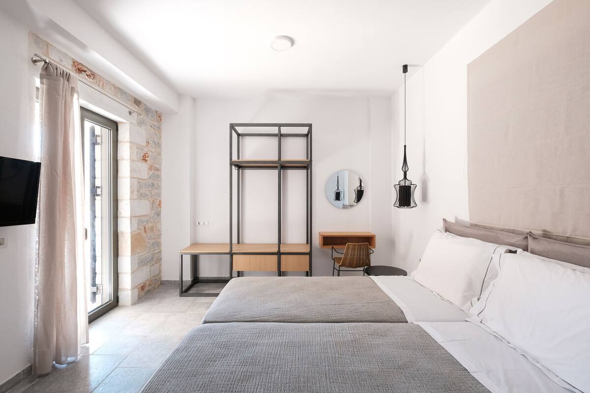 A modern bedroom with a bed, a desk, and a TV.