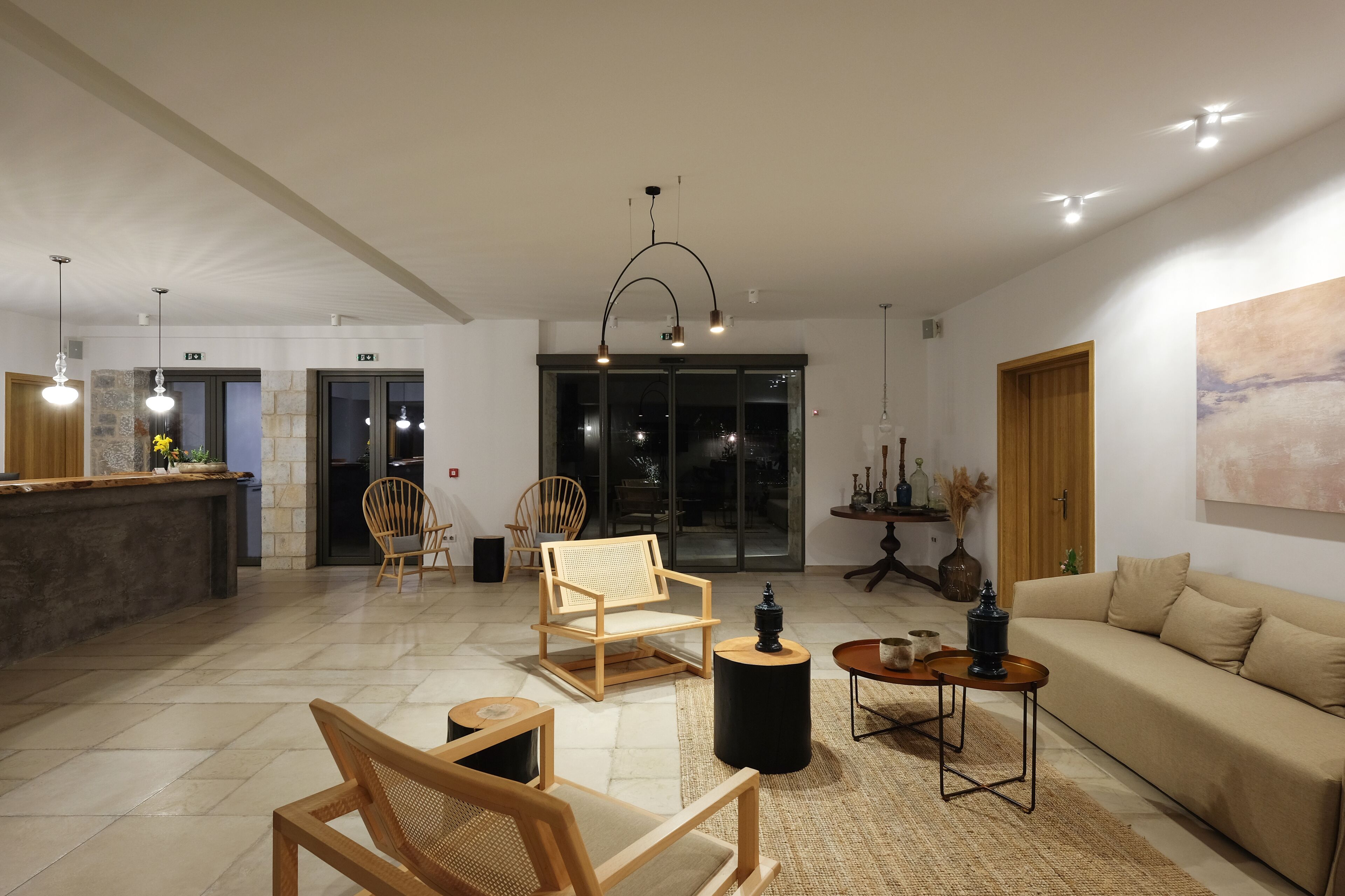 A spacious living area with a sofa, wooden chairs, a coffee table, and a kitchen area with a bar counter.