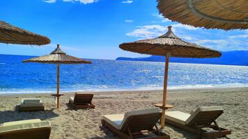 Na praia, espreguiçadeiras, guarda-sóis, toalhas de praia