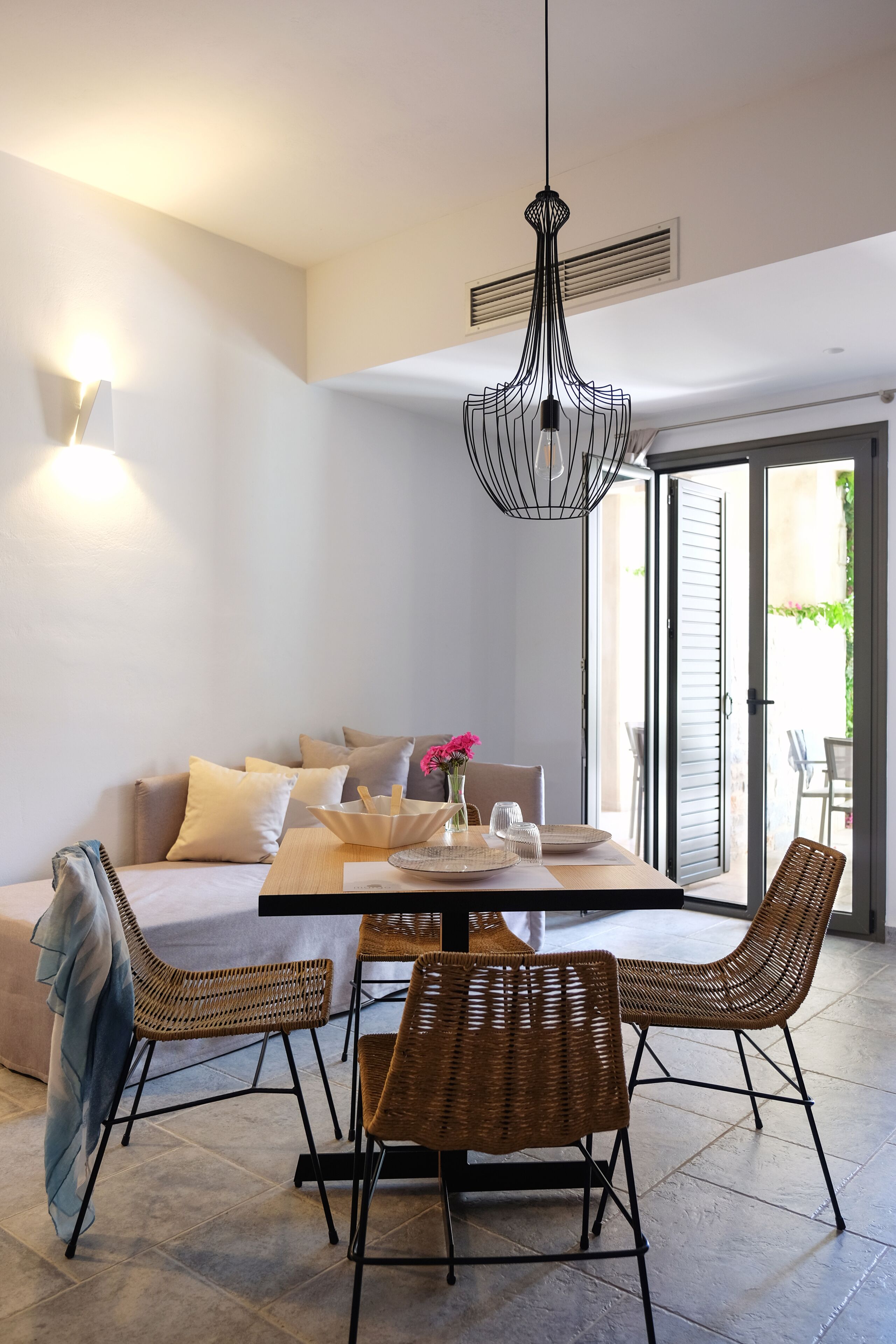 A dining area with a table, chairs, and a hanging light fixture.