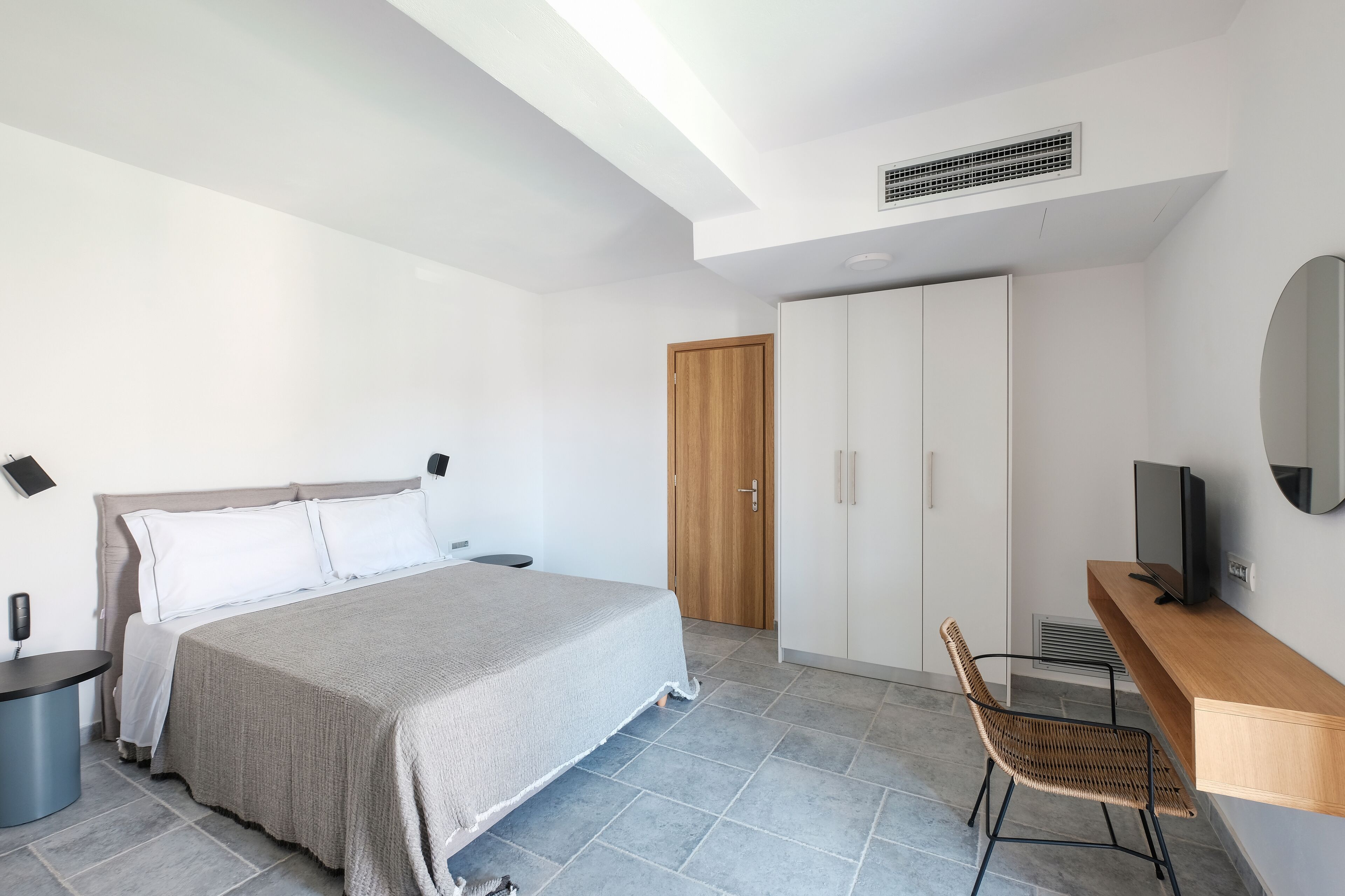 Un dormitorio moderno con cama, escritorio, silla, armario y televisor.