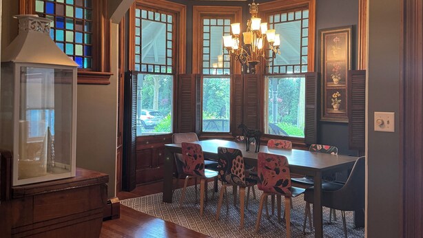 A dining area with a wooden table and chairs, a chandelier, and large windows with shutters. - Amazing location. Jackson St with pool.  Featured on #Staycation.  (Cape May)