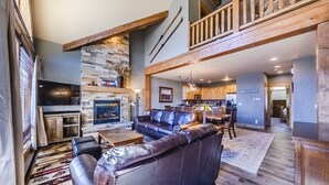 A spacious living room with a leather sofa, a fireplace, and a kitchen area. - Spacious Townhome with Private Hot Tub, minutes away from Winter Park Resort (Winter Park)