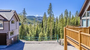 A building with a stone foundation and a wooden upper level, surrounded by a forested area and a clear sky. - Spacious Townhome with Private Hot Tub, minutes away from Winter Park Resort (Winter Park)