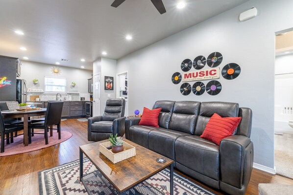 Un salon moderne avec un canapé en cuir, une table basse agrémentée d’une plante et un mur décoré de disques vinyle.