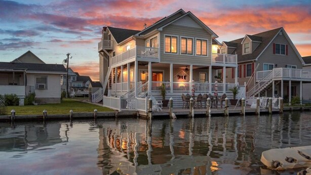 A waterfront property with a large house featuring a covered porch and multiple decks.