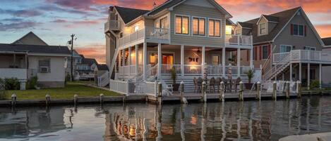 A waterfront property with a large house featuring a covered porch and multiple decks.