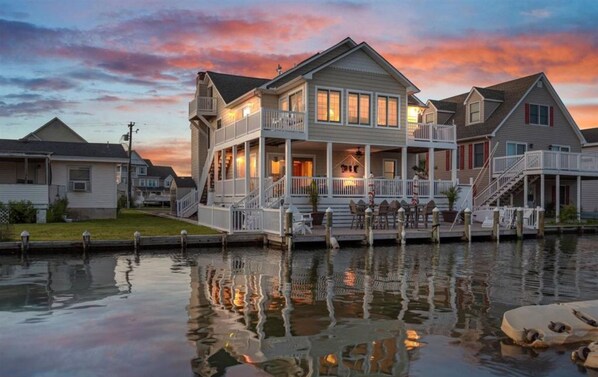 Une propriété située au bord de l’eau, avec une grande maison dotée d’un porche couvert et de plusieurs terrasses.